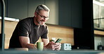 Phone, freelancer and smile with man in kitchen for online article, planning or research. Digital report, email newsletter and remote worker with mature person in home for project update or contact
