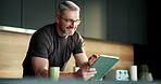 Tablet, freelancer and review with man in kitchen for online article, planning or research. Digital report, email newsletter and remote worker with mature person in home for  project update or post
