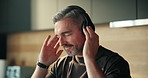 Music, dance and mature man in home with headphones, audio and playlist to relax on weekend. Happy, house and person listening to radio, sound and streaming subscription for positivity in kitchen