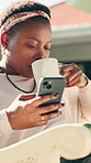 Mobile, drink coffee and black woman relax at backyard with video, social media and reading blog. Phone, tea and happy person by house outdoor for online search, ebook app and browsing internet
