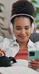 Headphones, phone and woman with dog on sofa in living room of home for break or streaming. App, music and smile of person stroking pet in apartment together for bonding, relax or subscription