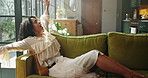 Yawning, woman and stretching on couch, home and tired in living room, resting or break in apartment. Calm, person and fatigue in lounge, relax and sleepy on sofa, chill and lazy on weekend in house
