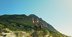 Hiking, men and hands raised in celebration on mountain for fitness goals, performance or mockup. Blue sky, friends or high five on cliff space for trekking success, teamwork achievement or low angle