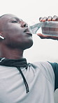 Fitness, black man and drink water in rain with earphones for music playlist, workout break or below. Person outdoor, beverage and audio tech with streaming service, album and hydration for exercise.