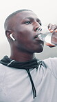 Fitness, man outdoor and drink water with earphones for music playlist, workout break or below. Black person, beverage and audio tech in rain with streaming service, album and hydration for exercise.