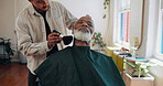 Man, barber and grooming with brush for beard, hygiene and facial hair removal with services at shop. People, tools and mature customer with equipment, hairstyle or trim with treatment at salon