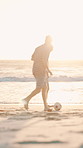 Having fun, soccer and sunset with friends on beach together for holiday, travel or vacation. Football, kicking and playing with group of happy people outdoor in nature for bonding, hobby or sports