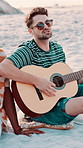 Beach, people or man playing guitar with sunglasses, summer vacation or holiday with musical entertainment. Friends, outdoor reunion or happy musician with acoustic performance, singing or chilling