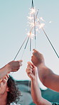 Friends, beach and hands with sparklers with group, bonding and reunion for celebration in nature. Summer holiday, social gathering or hangout with people, party and fireworks for vacation together