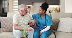 Senior man, nurse and discussion on sofa, support and assessment for wellness in retirement home. People, caregiver and comfort with assisted living, talk or consultation on couch in lounge at house