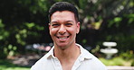Man, face and smile at park, outdoor and confidence in excited, pride and tourism at urban garden. Person, happy and portrait in summer for travel, holiday and sightseeing in nature in Malaysia