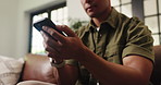 Hands, phone and texting on sofa, relax and check notification for web chat in living room at house. Person, smartphone and scroll with mobile app, contact and low angle for social media at apartment