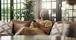 Phone, scrolling and thinking with woman on sofa in living room of home for social media browsing. App, idea and typing text message with happy person in apartment for communication or me time