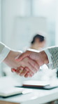 Business people, handshake and office with blur for partnership, deal or agreement together. Closeup, employees or colleagues shaking hands with conference for meeting, b2b or teamwork in workplace