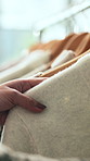 Clothes rack, hands and shopping with customer in boutique for decision or selection of material. Clothing, fashion and retail with person in store for choice or purchase of fabric and textile