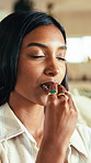 Chocolate, eating and satisfaction with Indian woman in home living room for craving or indulgence. Bite, candy and snack with happy person in apartment for delicious junk food, hunger or sweet treat