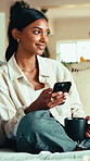 Coffee, phone and thinking with woman in home living room for internet or social media browsing. Drink, idea and typing with happy Indian person in apartment for communication or me time wellness