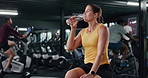 Woman, drinking water and fitness with hydration in gym for rest, recovery or workout break. Thirsty, active female person or mineral liquid with aqua, bottle or beverage for nutrition in health club