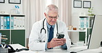 Doctor, smartphone and man in office, healthcare and research with social media. Mature person, professional and employee in hospital, cellphone and texting with digital app for schedule and internet