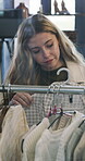 Shopping, choice and woman in boutique with clothes rack, outfit search and decision in trendy style. Retail, gen z and customer in store with apparel display, browsing or option for fashion purchase
