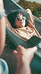 Relax, sun and woman in hammock with sunglasses, rest and comfortable nap in summer getaway. Sleep, sunny and people in resort with swing, unwinding and outdoor sunbathing in peaceful holiday.