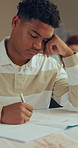 Bored, student and writing in classroom with notebook for biology activity, learning and difficult task. Tired, boy or teen in high school with fatigue from academic project, science course or study.