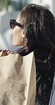 Fashion, shopping bag and back of woman for designer boutique, retail and wardrobe. Walk, sunglasses and luxury product with smile of customer in mall with sale, promotion and gift or discount