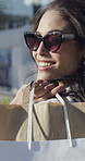 Happy, woman and walking with shopping bags, city and excited for promotion offer, purchase and deal. Outdoor, shopper and person with sunglasses on street, smile and searching for sale or discount
