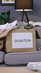 Donation, cardboard or box of clothes on couch, sustainable practice or social responsibility in sharing. Eco friendly, generosity or second hand apparel in home for reuse, philanthropy or charity