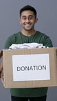 Face, man or clothes in donation box for non profit, community care or giving in studio. Cardboard, charity or happy person with package for help, volunteer or portrait for support on gray background