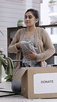 Woman, packing clothes and donation box in home for non profit, outreach and community care. Cardboard, charity and person with clothing for help, humanitarian aid or folding with package for support