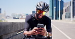 Cycling, texting and man in city with phone, message or social media scroll on workout break. Fitness, laugh and cyclist on bridge with tech, sportswear and wellness chat in energy recovery.