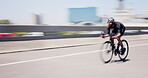 Athlete, man and speed on bicycle in city for cycling exercise, endurance challenge and motion blur. Fast cyclist, person and riding bike in road for triathlon training, sports performance or fitness
