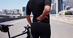 Person, cyclist and bicycle with back pain in city for bad posture, disomfort or strain. Active, cycling accident or biker with sore spine, injury or joint inflammation for backache in urban street