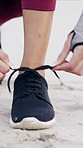 Person, hands and tying with shoes on beach for fitness, workout preparation or outdoor exercise. Closeup, active or runner getting ready with tie, sneaker or laces on sandy shore for training or run