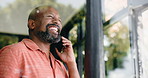 Funny, black man and phone call in home for talking to contact, news and joke with low angle. Mobile, chat and mature person laugh at story for humor, conversation and communication by window