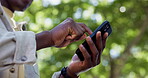 Hands, man outdoor and scroll with phone for social media post, virtual chat or online communication. Bokeh, person typing and browsing with tech in nature for text message, mobile app and low angle.