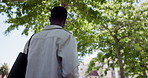 Back, student and black man in city, below and walking with urban town, scholarship or university. Travel, commute or African person with higher education, college or pedestrian with gen z or explore