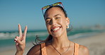 Face, girl and happy with peace sign on beach for travel adventure, weekend break or blowing kiss. Summer breeze, female tourist or smile at seaside for vacation getaway, fresh air or holiday freedom