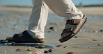 Beach, feet and man with sandals, walking and travel with vacation, weekend getaway and tourism. Ocean, shoes and person with summer holiday, explore and adventure with journey, nature and steps