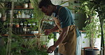Florist, man and water can at store with gardening, care or hydration for growth at sustainable startup. African person, botanist and entrepreneur with liquid, quality assurance and eco friendly shop
