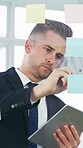 Glass wall, sticky notes and tablet with employee man in office for brainstorming or planning. App, storyboard and writing with business person in professional workplace for strategy development