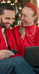 Credit card, laptop and couple in home with christmas shopping for gifts with online store. Laugh, debit and man with woman on computer for ecommerce order with xmas presents in apartment together.