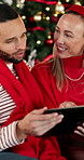 Christmas, tablet and happy couple talking in home, gift shopping and decision for sale with bokeh. Xmas, man and woman with technology in living room for festive purchase, ecommerce and holiday