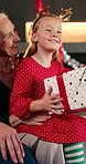 Girl, smile and giving with gift for Christmas, holiday celebration and bonding together. Grandmother, senior woman and present for granddaughter with xmas event, gratitude or festive reunion in home