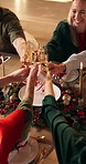 Champagne, cheers and hands of family at christmas dinner in home with celebration, holidays and festive. Sparkling wine, toast and top view of people with alcohol at xmas gathering in dining room.