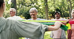 Elderly group, coach and resistance band with exercise in nature for workout class or training. Senior people, fitness or stretching with personal trainer for flexibility, health or wellness in park