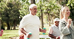 Elderly group, walking and dumbbells with personal trainer in park for cardio exercise or workout. Senior people, coach or training with weight for physical activity, health or wellness in nature