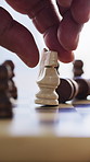 Closeup, home and person with chess game, hand and moving piece with victory. Contest, player and champion with strategy, checkmate and thinking with challenge, winning and pawn with competition