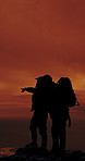 People, silhouette and point on mountain, hiking and direction for view, sunset sky and friends on adventure. Men, sightseeing and summit on rocks, hill or outdoor with space for trekking challenge